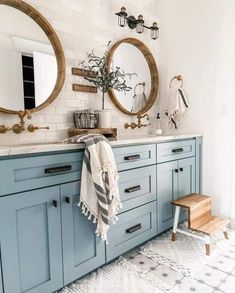 a bathroom with blue cabinets and two round mirrors