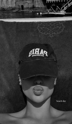 a black and white photo of a shirtless woman wearing a baseball cap with the word paris on it