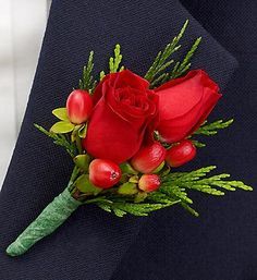 a boutonniere with red roses and greenery on the lapel of a man's suit