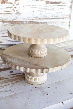 three tiered cake stand sitting on top of a white wooden table next to a window