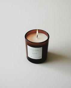 a candle that is sitting on a white surface next to a black and brown container