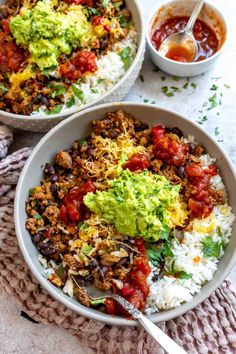 two bowls filled with rice, beans and guacamole on top of a table