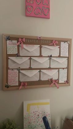 a bulletin board that has some paper on it and pink hearts hanging from the wall