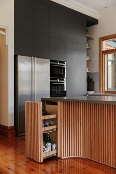 an open cabinet in the middle of a kitchen with wooden floors and cabinets on both sides