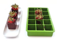 chocolate covered strawberries in an ice tray with flowers on top and another one sitting next to it