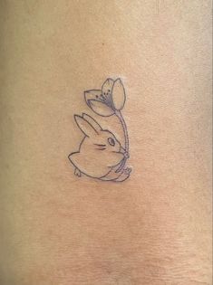 a small tattoo on the back of a woman's stomach with a rabbit holding a flower