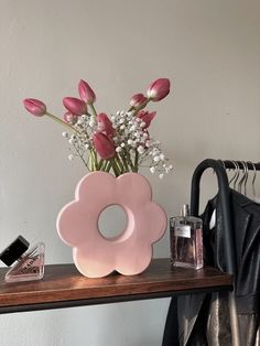 a pink flower vase sitting on top of a wooden table