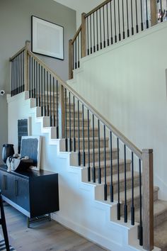 a living room with stairs and a tv on top of a dresser next to a table