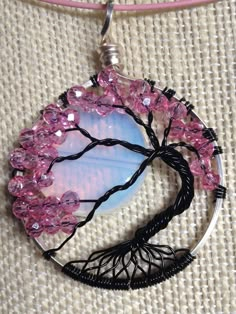 a tree with pink flowers is shown in the shape of a pendant