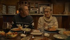 a man and woman sitting at a table with plates of food