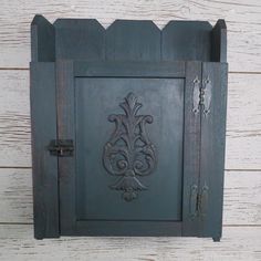 an old wooden cabinet with ornate carvings on the front and sides, against a white wood wall