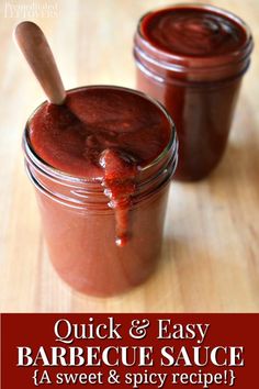 two jars filled with barbecue sauce sitting on top of a wooden table