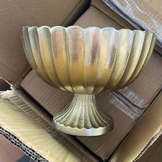 a large metal bowl sitting on top of a cardboard box with other boxes in the background