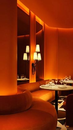 a dimly lit restaurant with round tables and orange walls