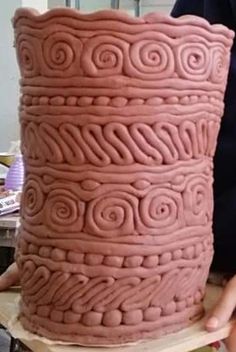 a large pink vase sitting on top of a wooden table next to a person holding it