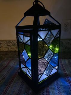 a stained glass lantern sitting on top of a table next to a light switch box