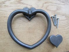 a heart shaped metal object sitting on top of a wooden table next to screws