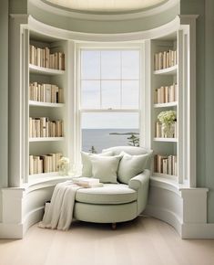 a white couch sitting under a window next to a book shelf filled with lots of books