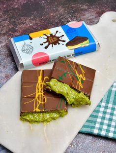 two pieces of chocolate and guacamole on a cutting board next to a carton of milk