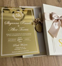 an open box with a ribbon on it next to a wedding card and its envelope