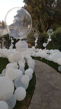 white balloons floating in the air near a walkway