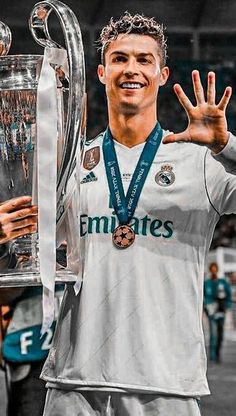 the soccer player is holding his trophy in front of him and posing with it's hands up