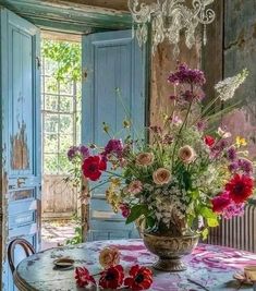 a vase filled with flowers sitting on top of a table next to a blue door