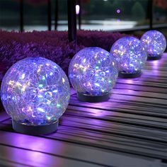 several lights that are on some kind of wooden plank in front of purple flowers and grass