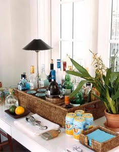 a table with bottles, glasses and other items sitting on top of it in front of a window