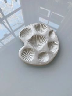 a white ceramic dish sitting on top of a table next to a glass window in the background