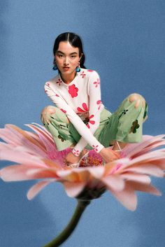 a woman sitting on top of a pink flower