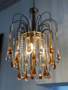 a chandelier hanging from the ceiling with lots of glass drops on it and lights