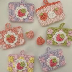 four crocheted purses with apples and cherries on the top one is pink, green, yellow and white