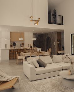 a living room filled with furniture next to a kitchen and dining room table in front of an open floor plan