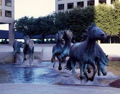 three statues of horses are in the water