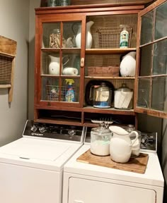 a washer and dryer sitting next to each other in a room with wooden shelves