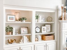 a white book shelf filled with lots of books and pictures next to a clock on top of it