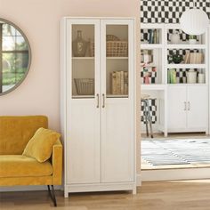 a living room with a yellow chair and white bookcase next to a mirror on the wall