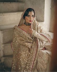 a woman in a gold and red sari is posing for the camera with her hands on her hips