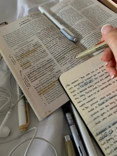 an open book with writing on it next to headphones and earbud plugs