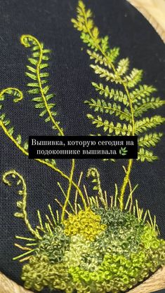 a close up of a embroidery design on a black cloth with green plants and grass