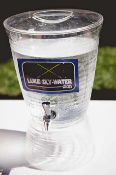 a water dispenser sitting on top of a table next to a green field