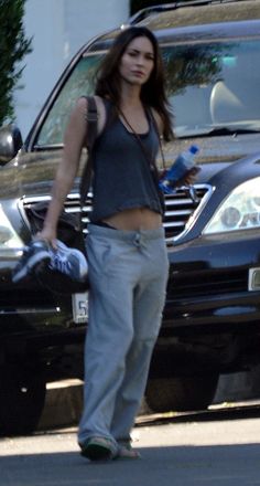 a woman standing in front of a black car