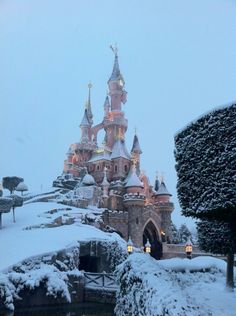 the castle is covered in snow and has lights on it's towers, which are lit up at night