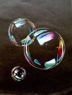 two soap bubbles sitting on top of a black surface