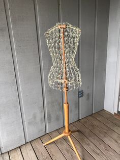 a mannequin made out of wire and wood on a wooden floor next to a wall