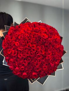 a woman holding a large bouquet of red roses