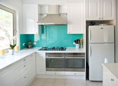 a kitchen with white cabinets and teal backsplashes on the walls, along with a stove top oven