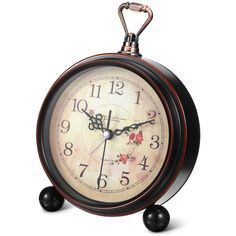 an old fashioned alarm clock with flowers on the face and hands, is shown against a white background