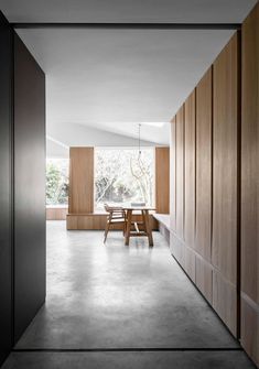 an empty hallway leading to a dining room with wooden walls and doors on both sides